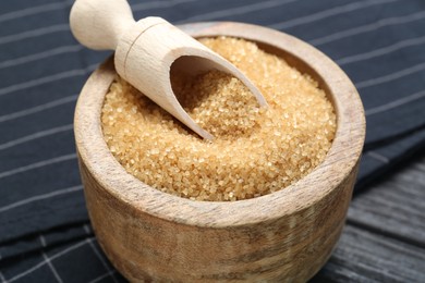 Photo of Brown sugar in bowl and scoop on table, closeup