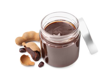 Photo of Jar of tasty tamarind sauce and fresh pods isolated on white