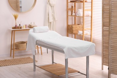 Photo of Comfortable massage table with clean towels in spa center