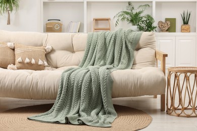 Photo of Comfortable sofa, blanket and side table in living room