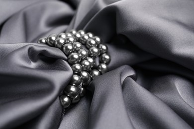 Photo of Beautiful pearls with grey silk as background, closeup