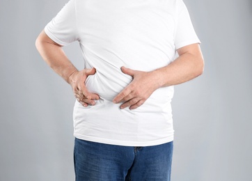Photo of Fat senior man on grey background, closeup. Weight loss