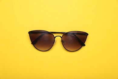 Photo of Stylish sunglasses on yellow background, top view