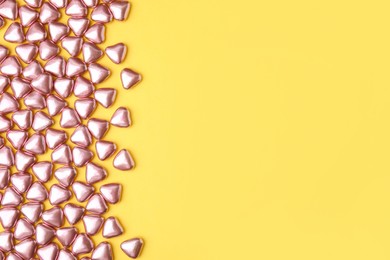 Photo of Many delicious heart shaped candies on yellow background, flat lay. Space for text