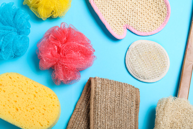 Photo of Flat lay composition with plastic and natural shower sponges on light blue background. Recycling concept