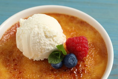 Photo of Delicious creme brulee with scoop of ice cream, fresh berries and mint on light blue background, closeup