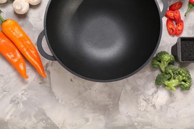 Photo of Wok and different products on grey textured table, flat lay. Space for text