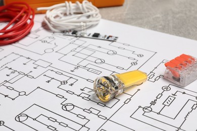Photo of Wiring diagram, wires and other electrician's equipment on grey table, closeup