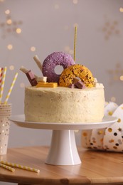 Photo of Delicious cake decorated with sweets and festive items on wooden table