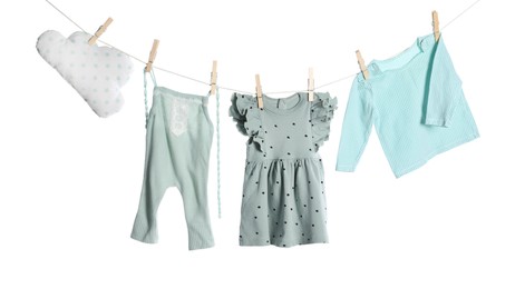Photo of Different baby clothes and cloud shaped pillow drying on laundry line against white background