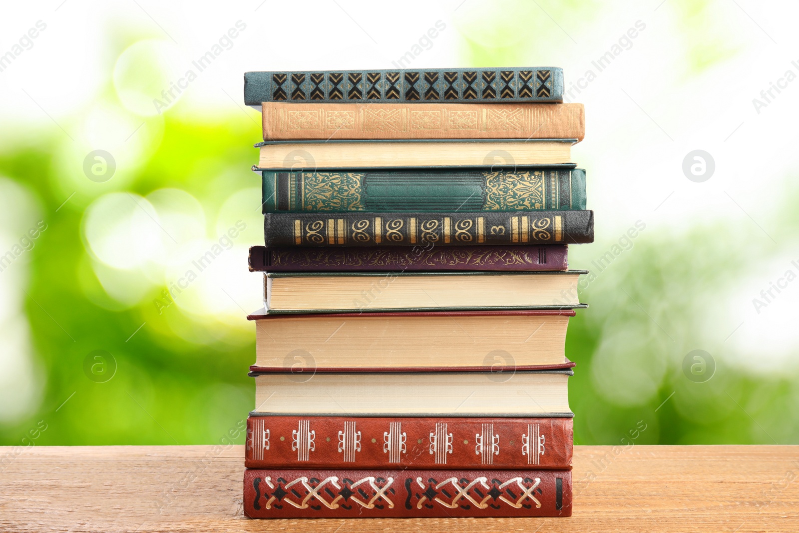 Image of Collection of different books on wooden table against blurred green background