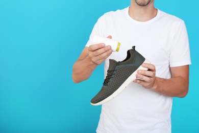 Photo of Man putting powder freshener into shoe on color background