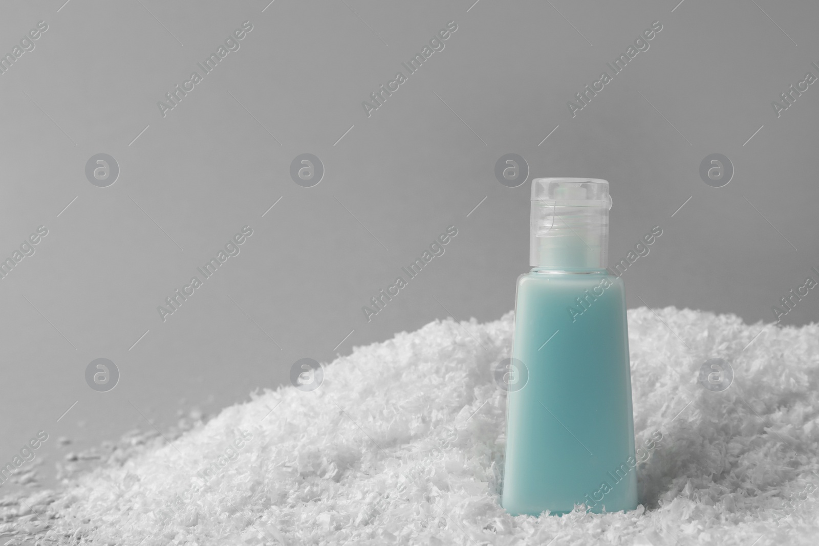 Photo of Winter skin care. Hand cream on artificial snow against light grey background, space for text