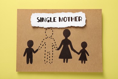 Photo of Being single mother concept. Card with drawn family after divorce on yellow background, top view