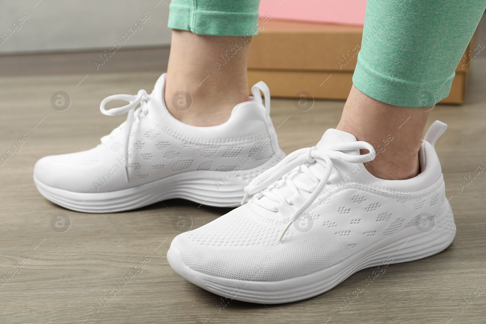 Photo of Woman wearing stylish sport shoes indoors, closeup