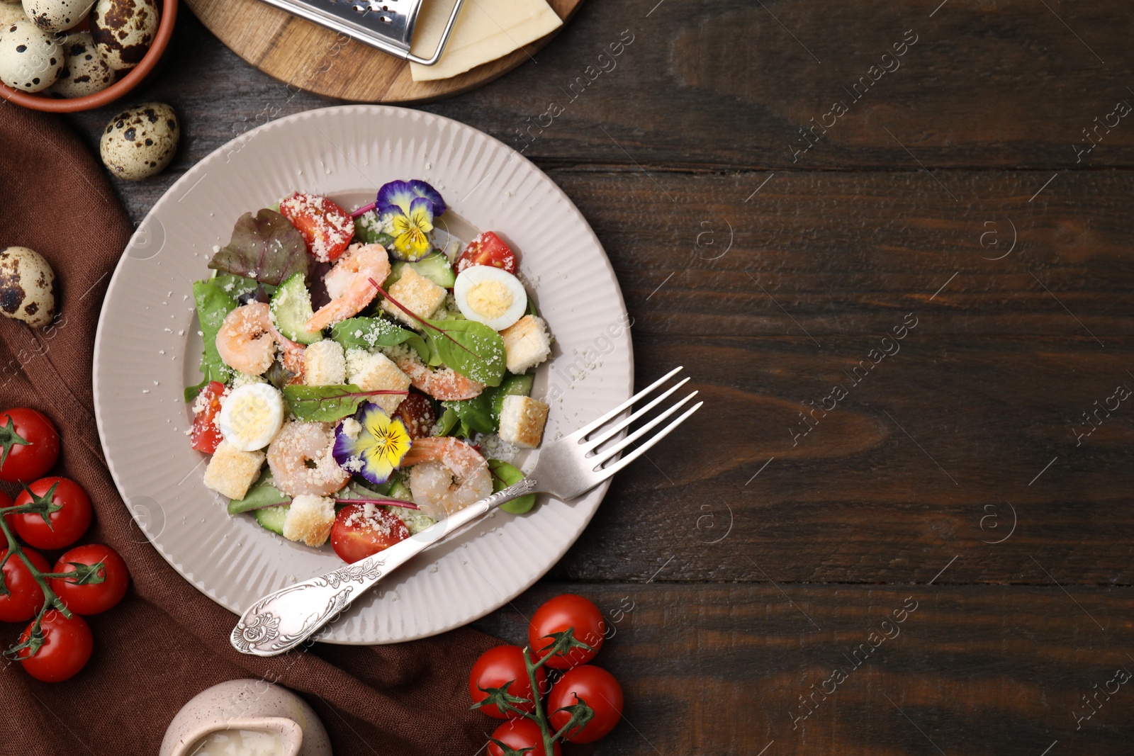 Photo of Delicious Caesar salad with shrimps and ingredients on wooden table, flat lay. Space for text