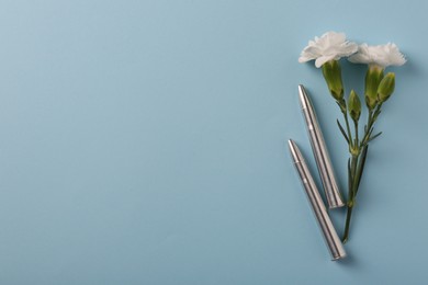 Photo of Bullets and beautiful flowers on light blue background, flat lay. Space for text