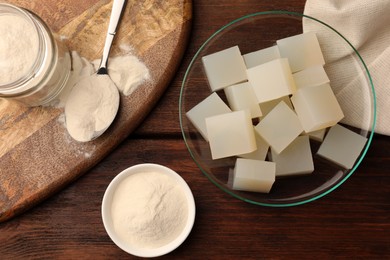 Photo of Agar-agar jelly cubes and powder on wooden table, flat lay