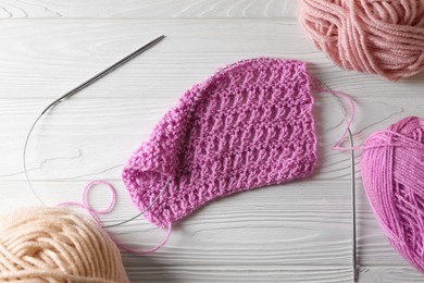 Photo of Soft yarns, knitting and metal needles on white wooden table, flat lay