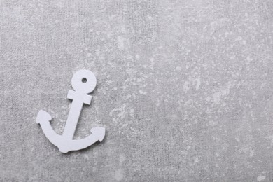 Photo of Anchor figure on light grey table, top view. Space for text