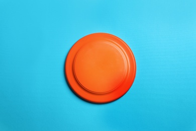 Photo of Orange plastic frisbee disk on light blue background, top view