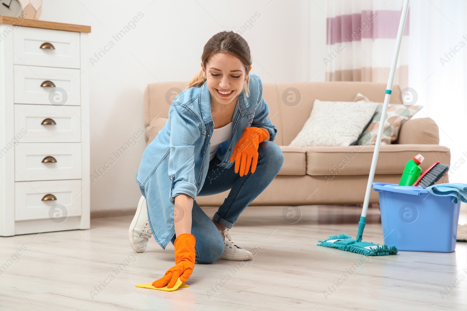 Young woman washing floor with rag and detergent in living room. Cleaning service Photo of Young woman washing floor with rag and detergent in living room. Cleaning service
