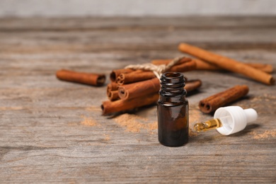Photo of Bottle with cinnamon oil and sticks on wooden table