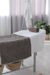 Photo of Comfortable massage table with clean towels in spa center