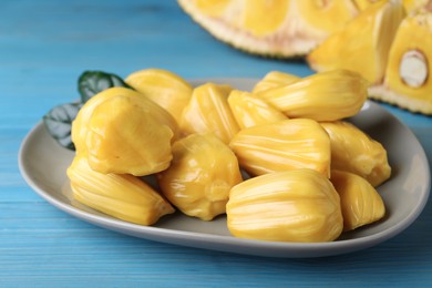 Photo of Delicious exotic jackfruit bulbs on light blue wooden table