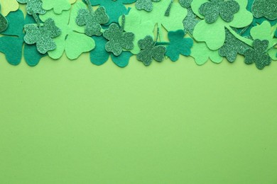 Photo of St. Patrick's day. Decorative clover leaves on green background, top view. Space for text