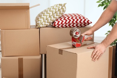 Photo of Man packing carton box indoors, closeup. Moving day