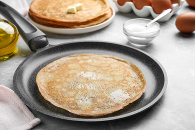 Photo of Delicious thin pancake on grey marble table, closeup