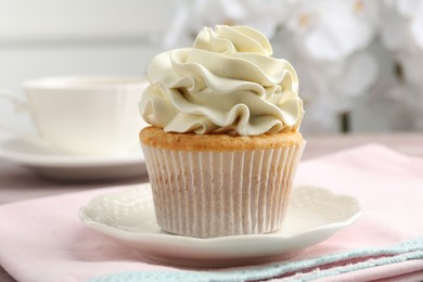 Photo of Tasty cupcake with vanilla cream on table, closeup
