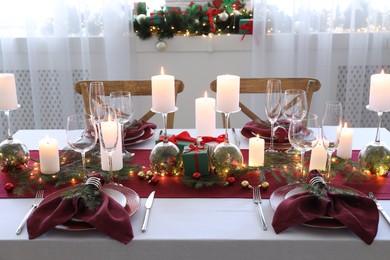 Photo of Christmas table setting with burning candles and festive decor