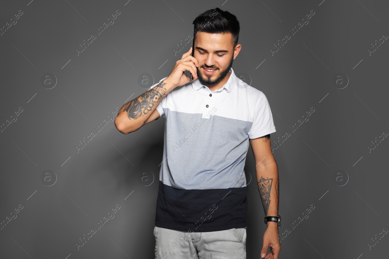 Photo of Portrait of handsome young man with mobile phone on gray background