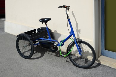 Photo of Blue bicycle with crate and lock near building outdoors