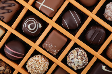 Photo of Box with different chocolate candies as background, top view