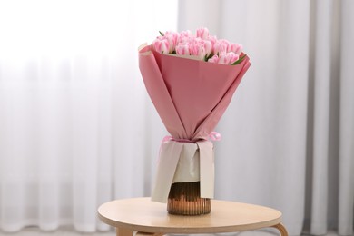 Photo of Beautiful bouquet of fresh pink tulips on table indoors