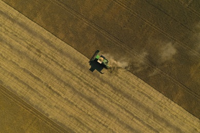 Photo of Beautiful aerial view of modern combine harvester working in field on sunny day. Agriculture industry