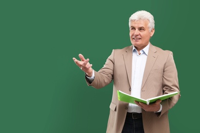 Photo of Portrait of senior teacher with notebook at green chalkboard, space for text
