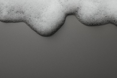 Photo of Fluffy soap foam on grey background, top view. Space for text
