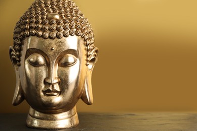 Buddha statue on table against golden background. Space for text