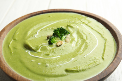 Photo of Bowl of delicious broccoli cream soup with pumpkin seeds, closeup