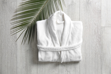 Photo of Flat lay composition with clean folded bathrobe on light wooden background