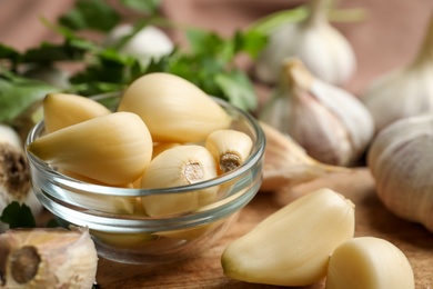 Photo of Fresh peeled garlic cloves in bowl on table, closeup. Organic product
