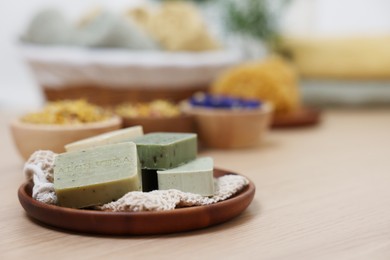 Photo of Tray with soap bars on light wooden table, space for text. Spa therapy