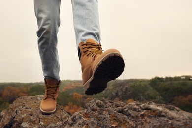 Photo of Man wearing stylish hiking boots on steep cliff, closeup