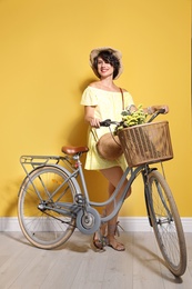Photo of Portrait of beautiful young woman with bicycle near color wall