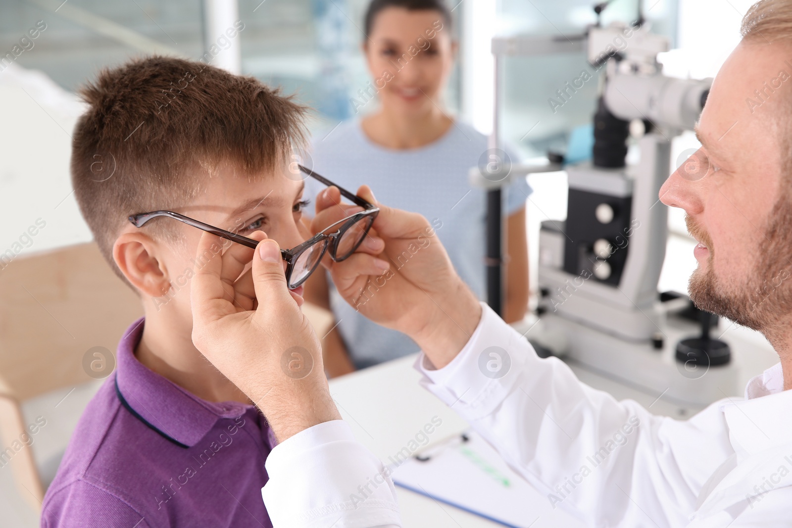 Photo of Children's doctor putting glasses on little boy in clinic