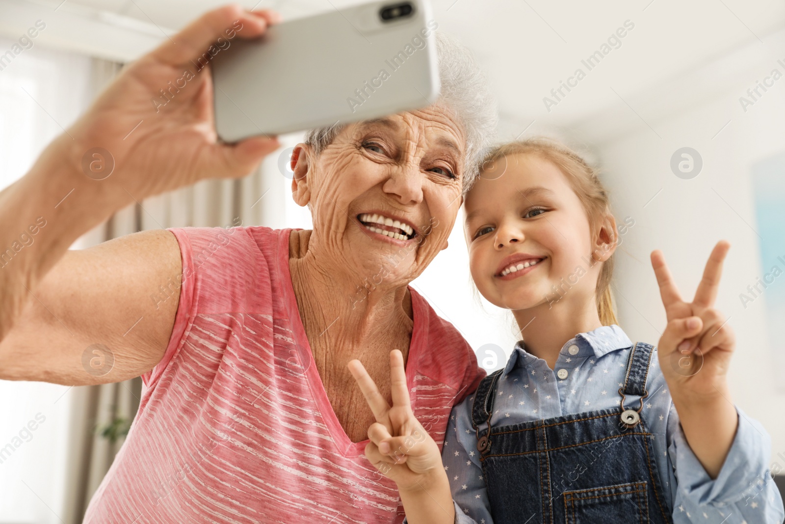 Photo of Cute girl and her grandmother taking selfie  at home